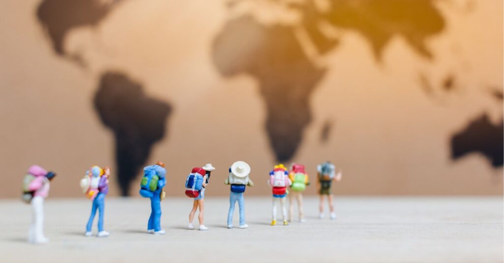 Muñecos que representan turistas frente a un mapa